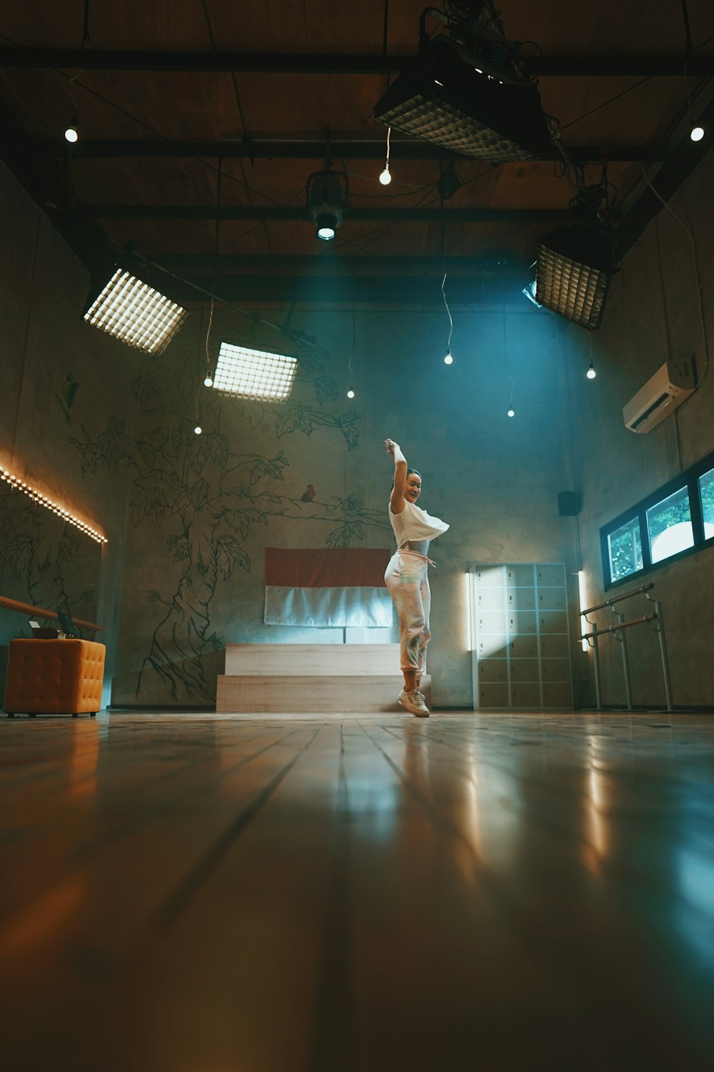 man in white long sleeve shirt and white pants jumping on brown wooden floor