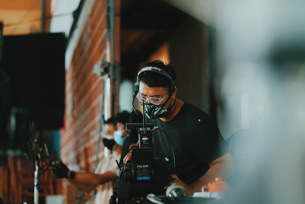 homem na camisa preta vestindo fones de ouvido pretos segurando câmera dslr preta