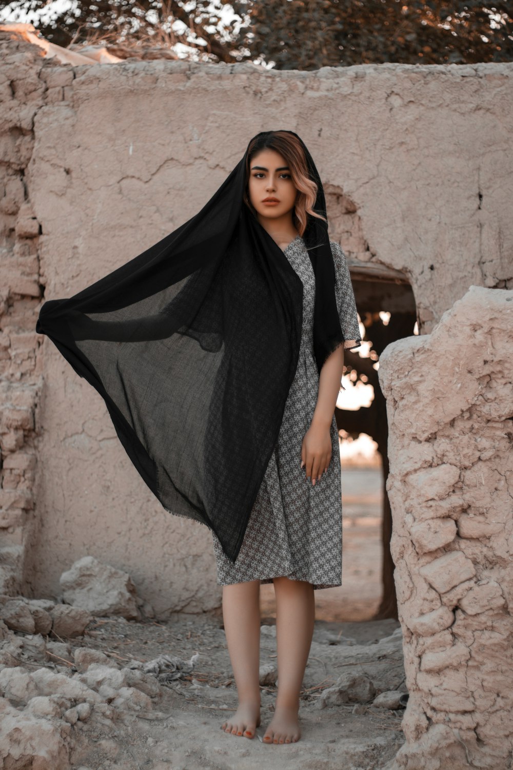 woman in black hijab standing beside brown rock