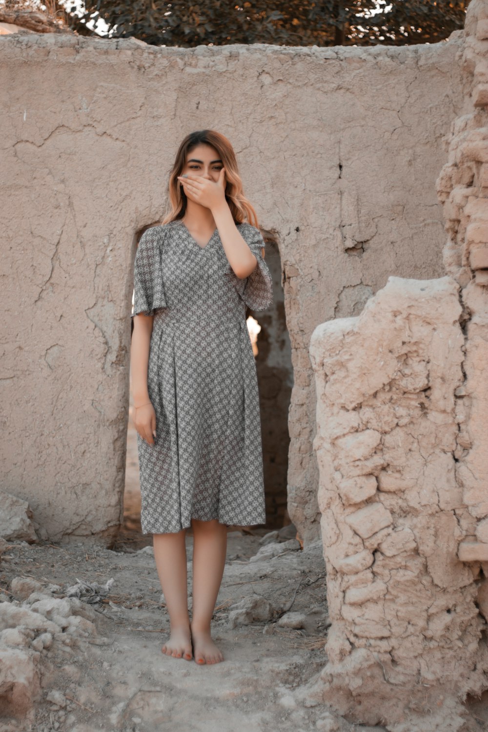 woman in black and white checkered dress standing beside brown concrete wall during daytime