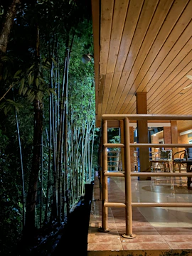 A luxurious bamboo deck with integrated lighting and minimalist patio cover, set against a backdrop of deep royal purple twilight.