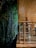 A cozy wooden deck is adjacent to a dense bamboo forest. The scene is warmly lit, with bamboo chairs arranged on the tiled floor and wooden railings lining the edge.