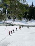 people playing ice hockey on snow covered field during daytime