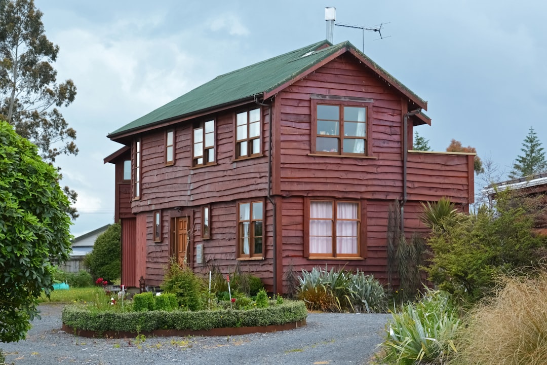 brown wooden house near green plants during daytime