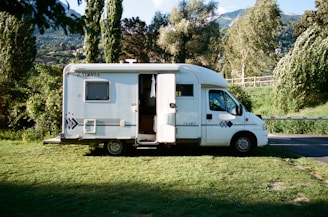 white and brown rv trailer on green grass field during daytime