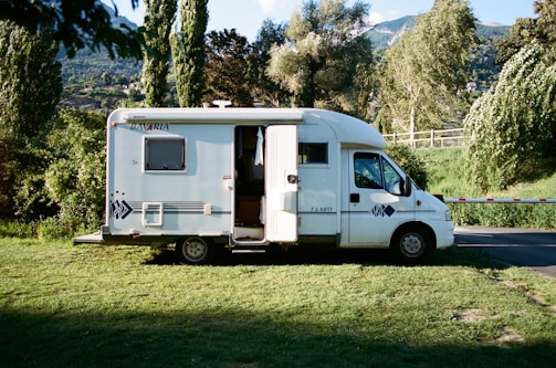 white and brown rv trailer on green grass field during daytime