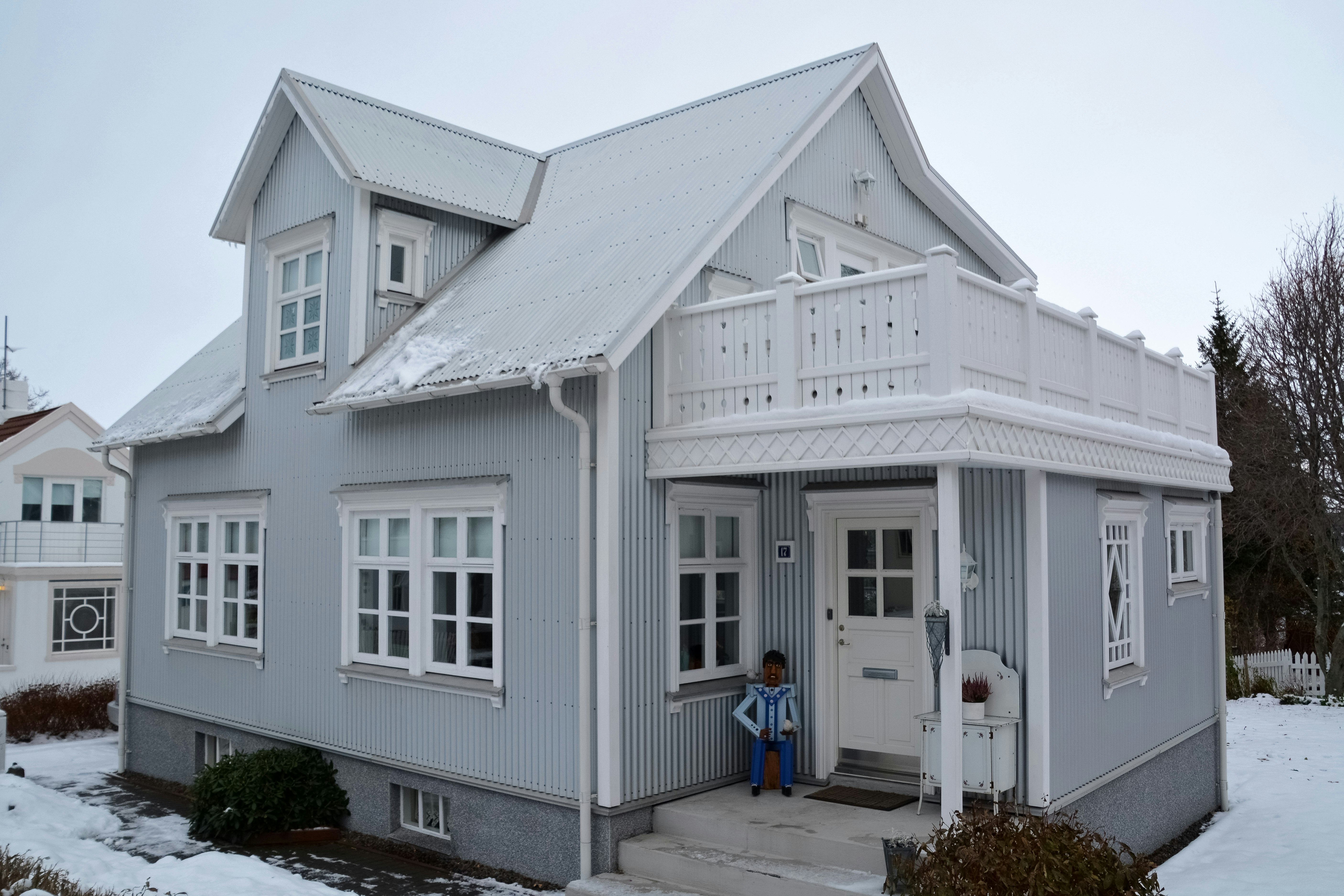 white wooden house with green plants in front