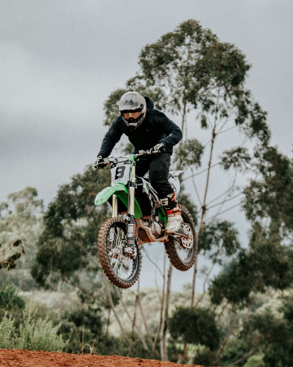 man in black jacket riding green motocross dirt bike