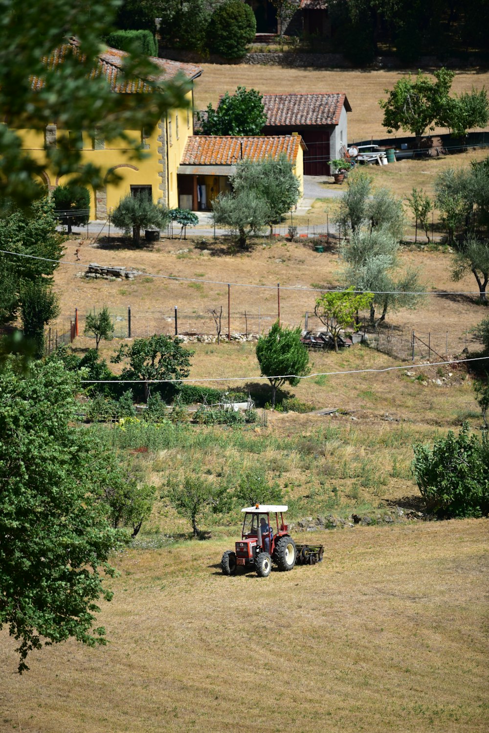 red and black tractor on brown field near green trees during daytime