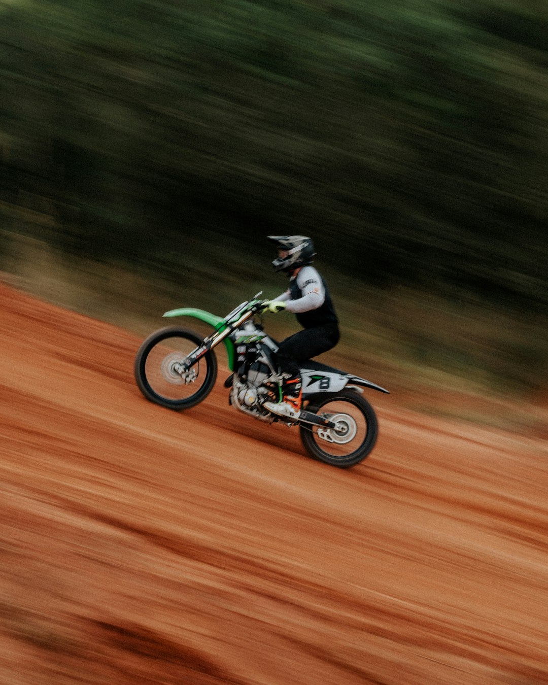 man riding motocross dirt bike on brown field during daytime
