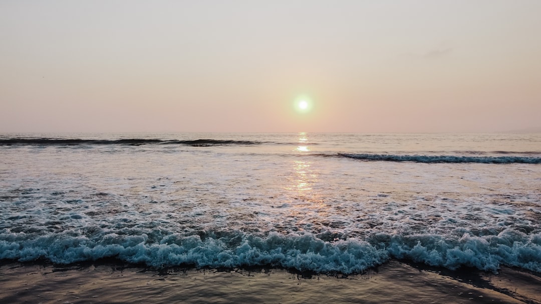 ocean waves crashing on shore during sunset