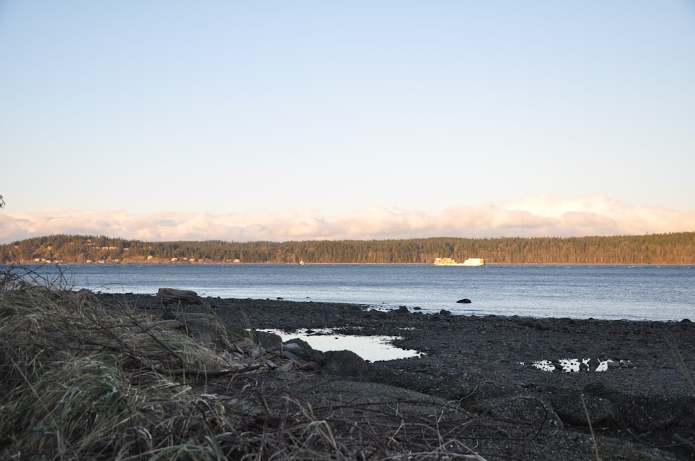 body of water near mountain during daytime