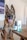 A German Shepherd dog sits in a room, its tongue out and expression relaxed. In the foreground, there is a bottle and a box of CBD oil for pets labeled 'Resilience' on a wooden table. The background includes a blurry portion of a TV screen and indoor furniture.
