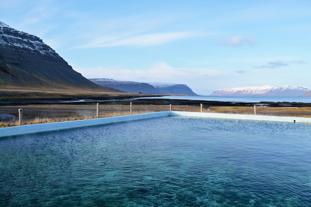 body of water near mountain under blue sky during daytime