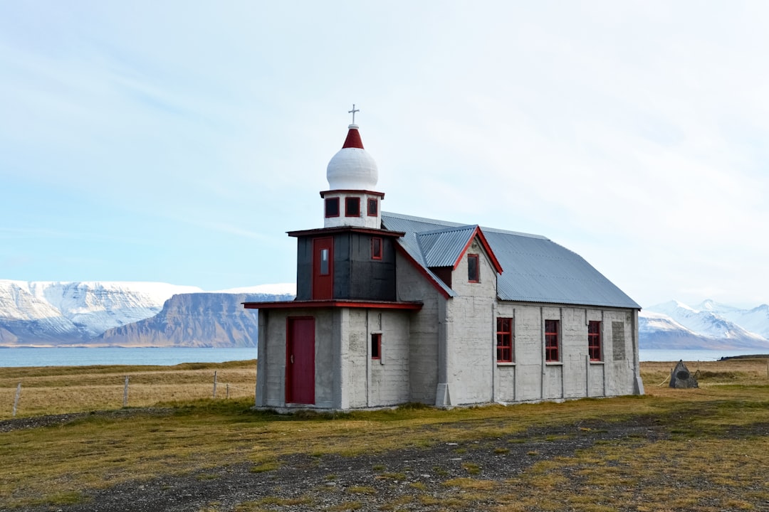 white and red concrete building near green grass field and mountain during daytime