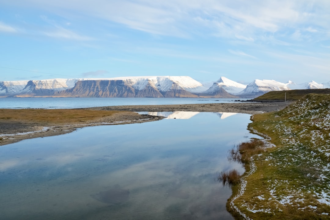 snow covered mountain near lake under blue sky during daytime