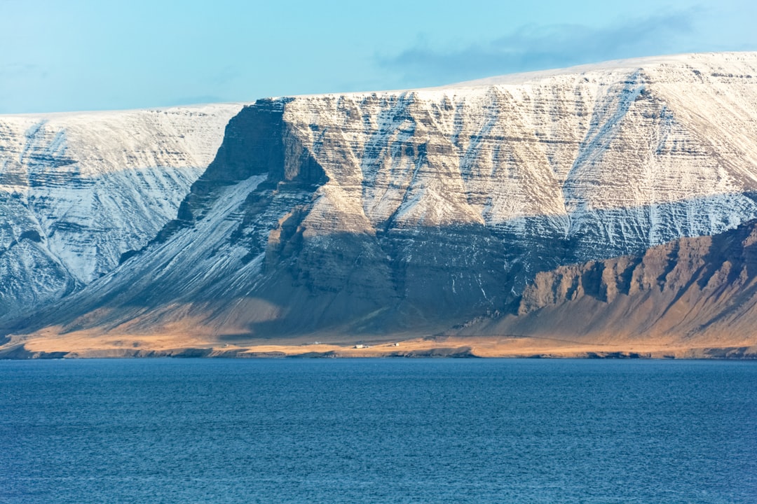 brown and white rocky mountain beside blue sea under blue sky during daytime