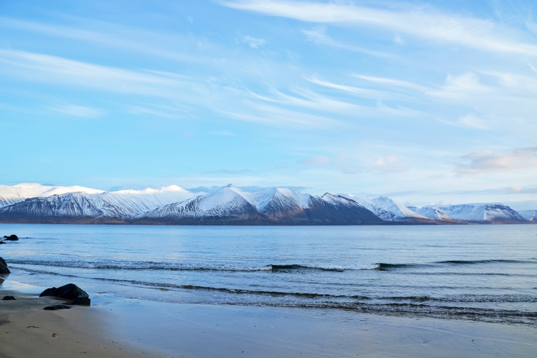 snow covered mountain near body of water during daytime