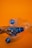 Three crumpled plastic bottles with blue caps are positioned against a bright orange background, creating a vivid contrast.