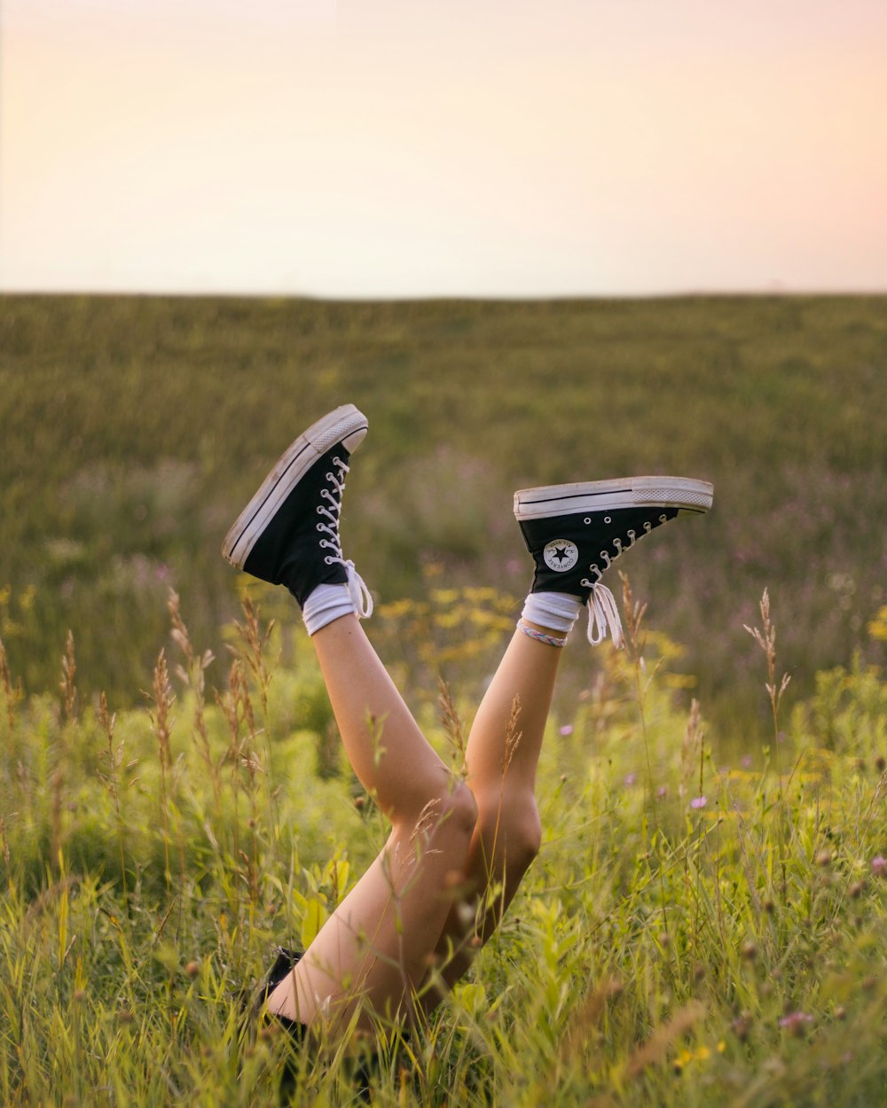 person in black and white nike sneakers sitting on green grass field during daytime