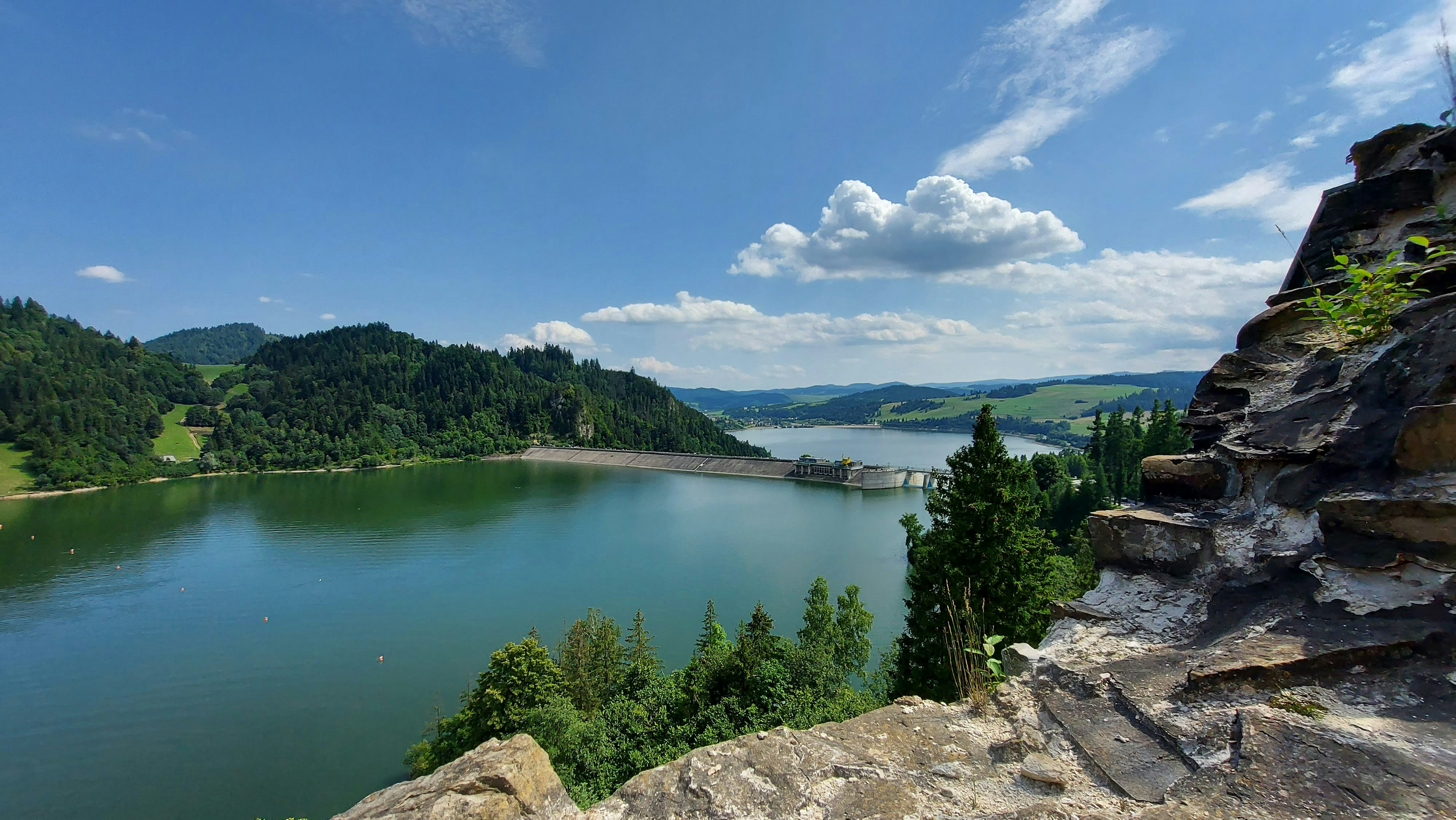 green lake surrounded by green trees under blue sky during daytime