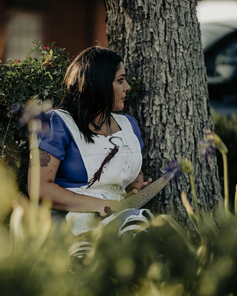 woman in blue and white t-shirt sitting on green grass field during daytime