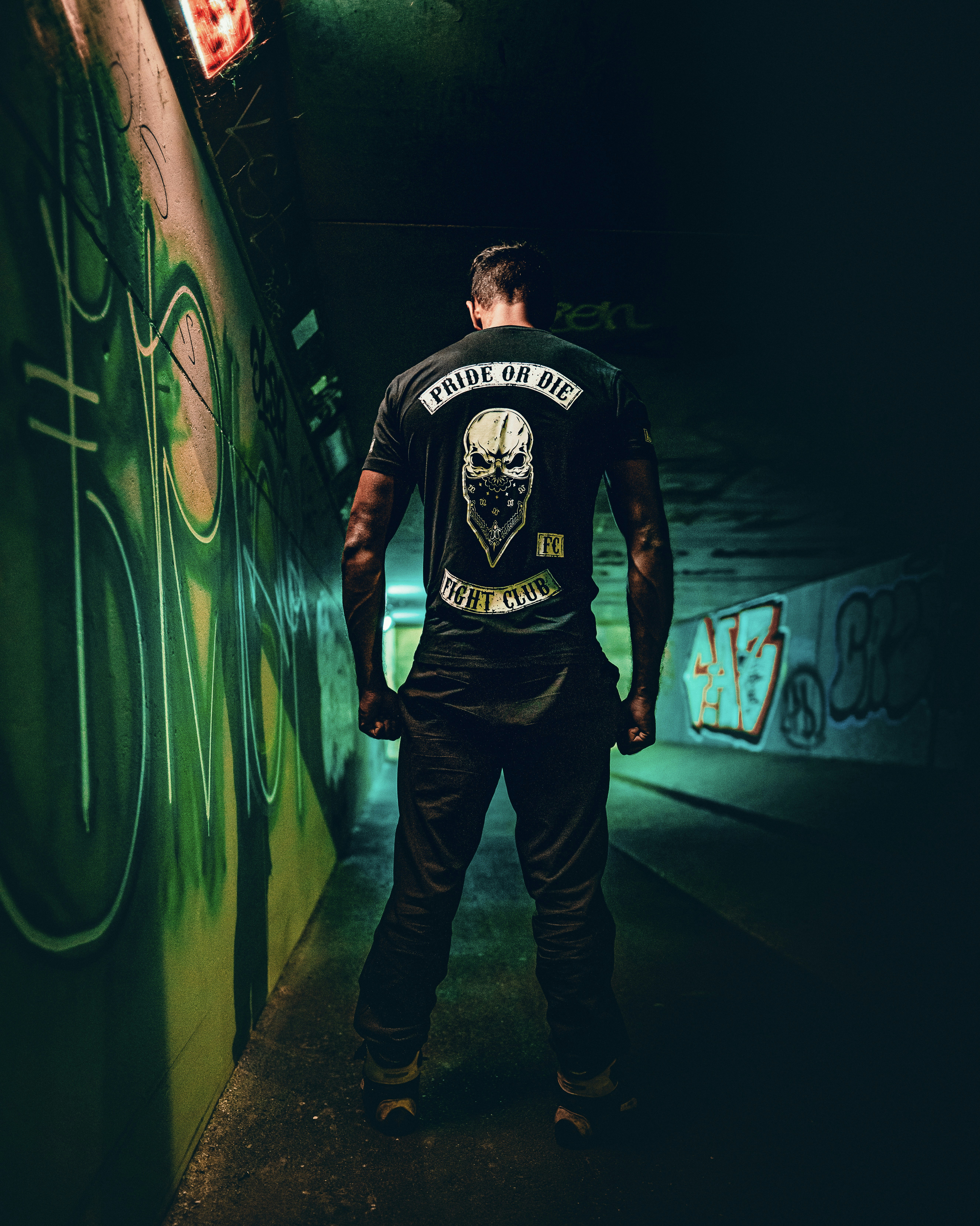 Homme en t-shirt à col rond noir et blanc et jean en denim bleu debout à côté de néon