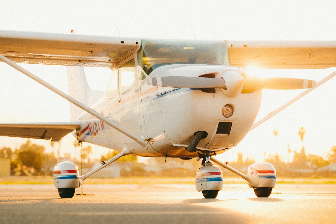 A small white single-engine Cessna parked on the ramp at a general aviation airport