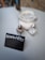 A small blackboard sign with white chalk that reads 'RESERVIERT' is placed on a light-colored table. Next to the sign, there are a few small glass containers, possibly for condiments.