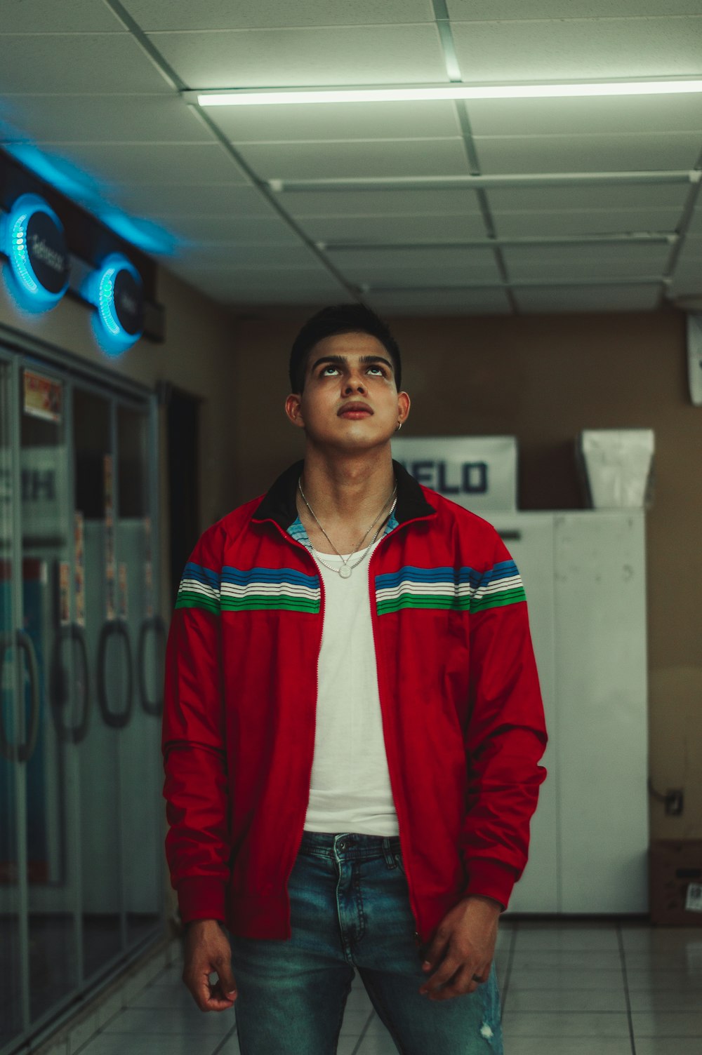 man in red zip up jacket standing near blue door