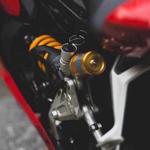 Close-up of motorcycle suspension system with shiny metal parts in a workshop setting.
