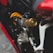 A close-up view of a motorcycle suspension system featuring a bright orange coil spring and a metallic component with intricate detailing. The surrounding areas are parts of the motorcycle, including a red body panel and other metallic elements.