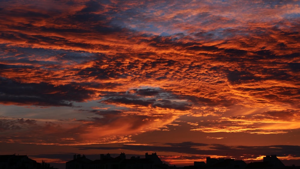 silhouette of buildings under orange and blue cloudy sky during sunset