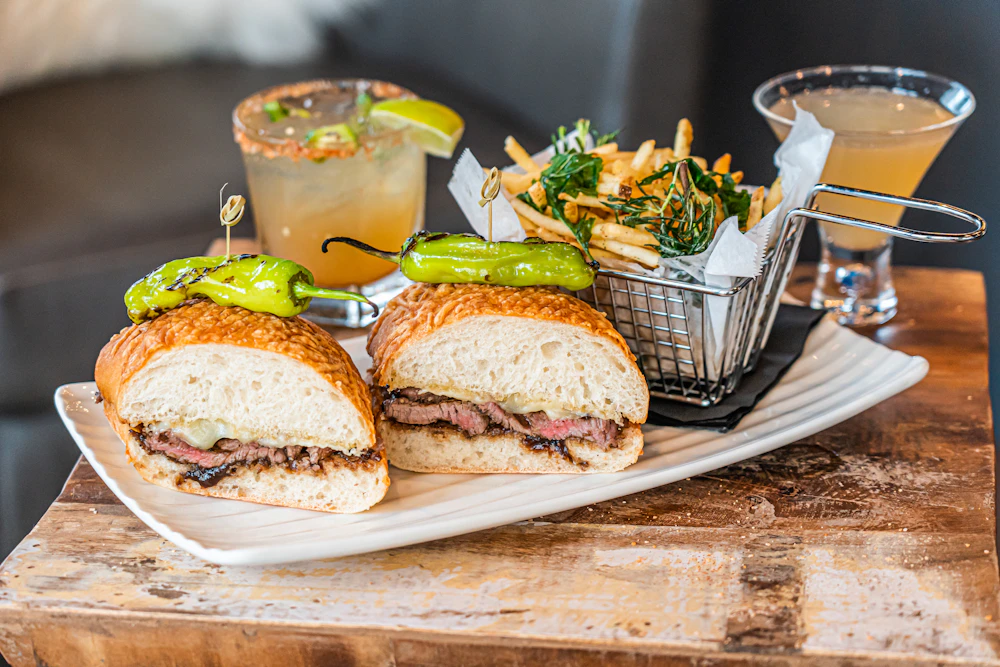 Sandwiches, fries and cocktails served on a bar table