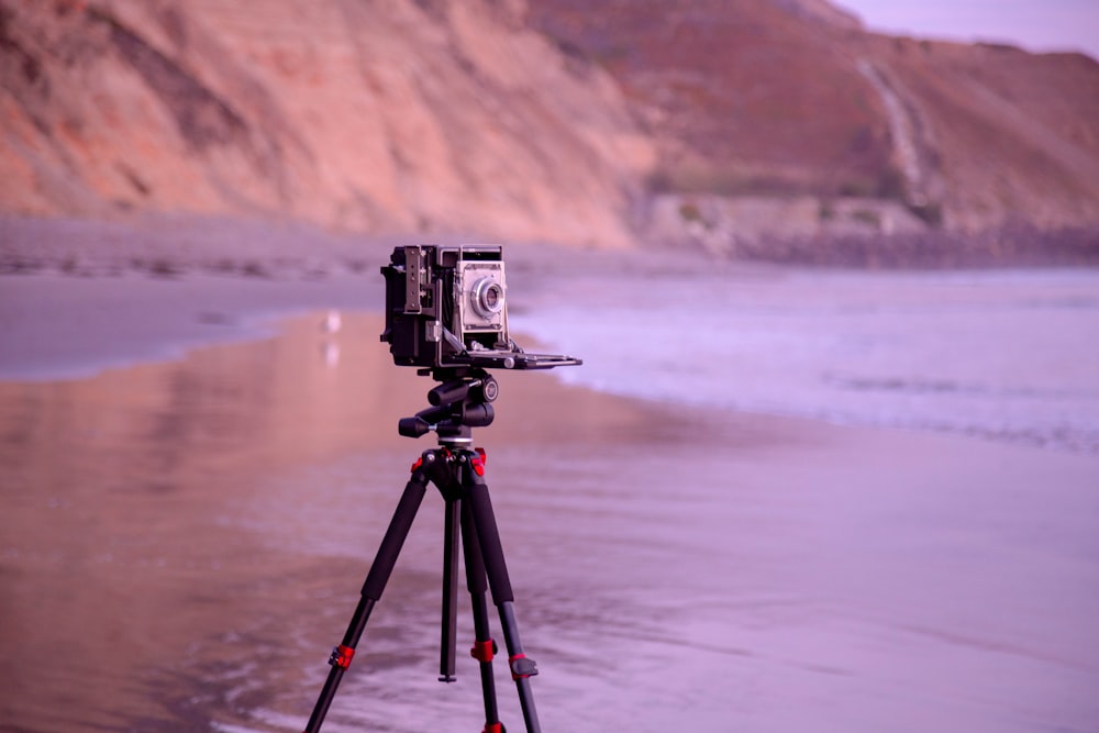 macchina fotografica nera sul treppiede sulla spiaggia durante il giorno