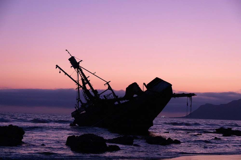 silhouette of ship on sea during sunset