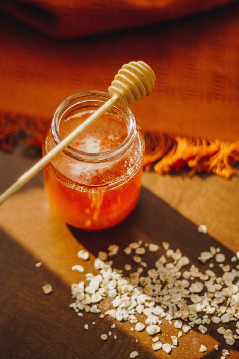Artisanal honey jars arranged on a wooden table with natural light highlighting the golden hues of the honey.