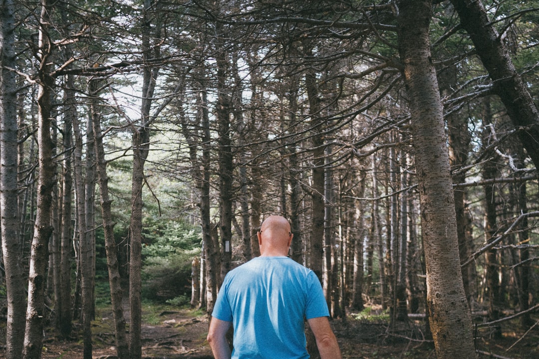 man in blue crew neck t-shirt standing in the woods during daytime