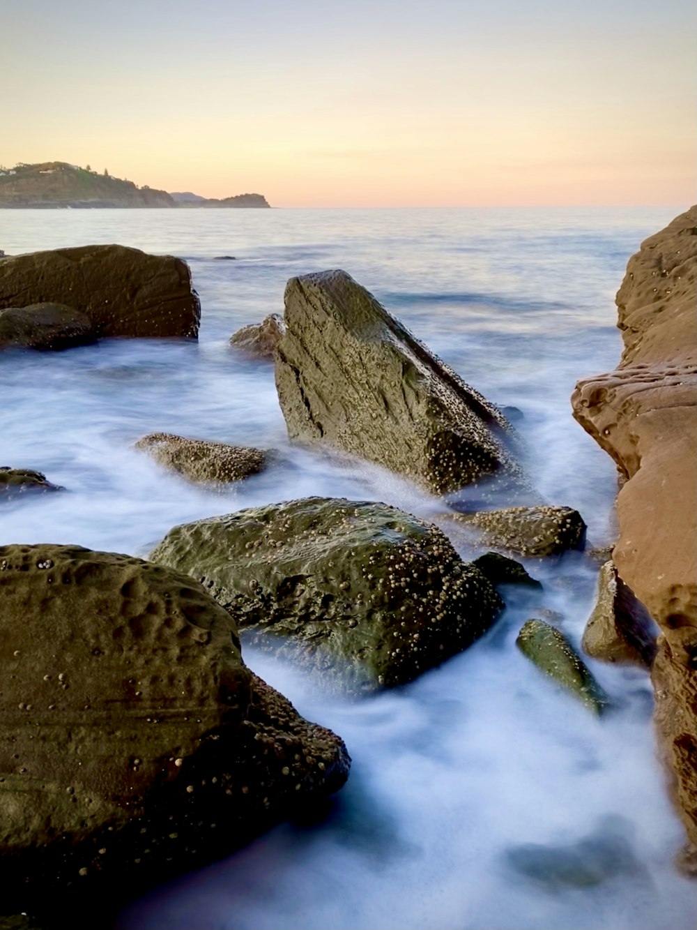 brown rock formation on body of water during daytime