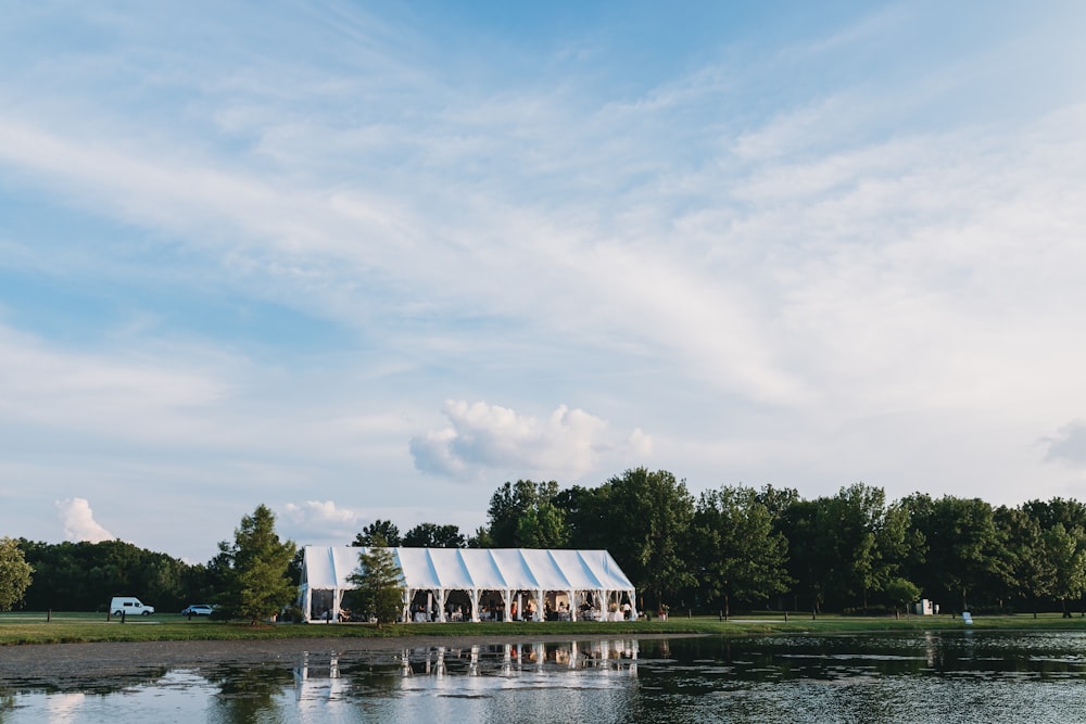 white and brown wooden house near green trees and body of water during daytime