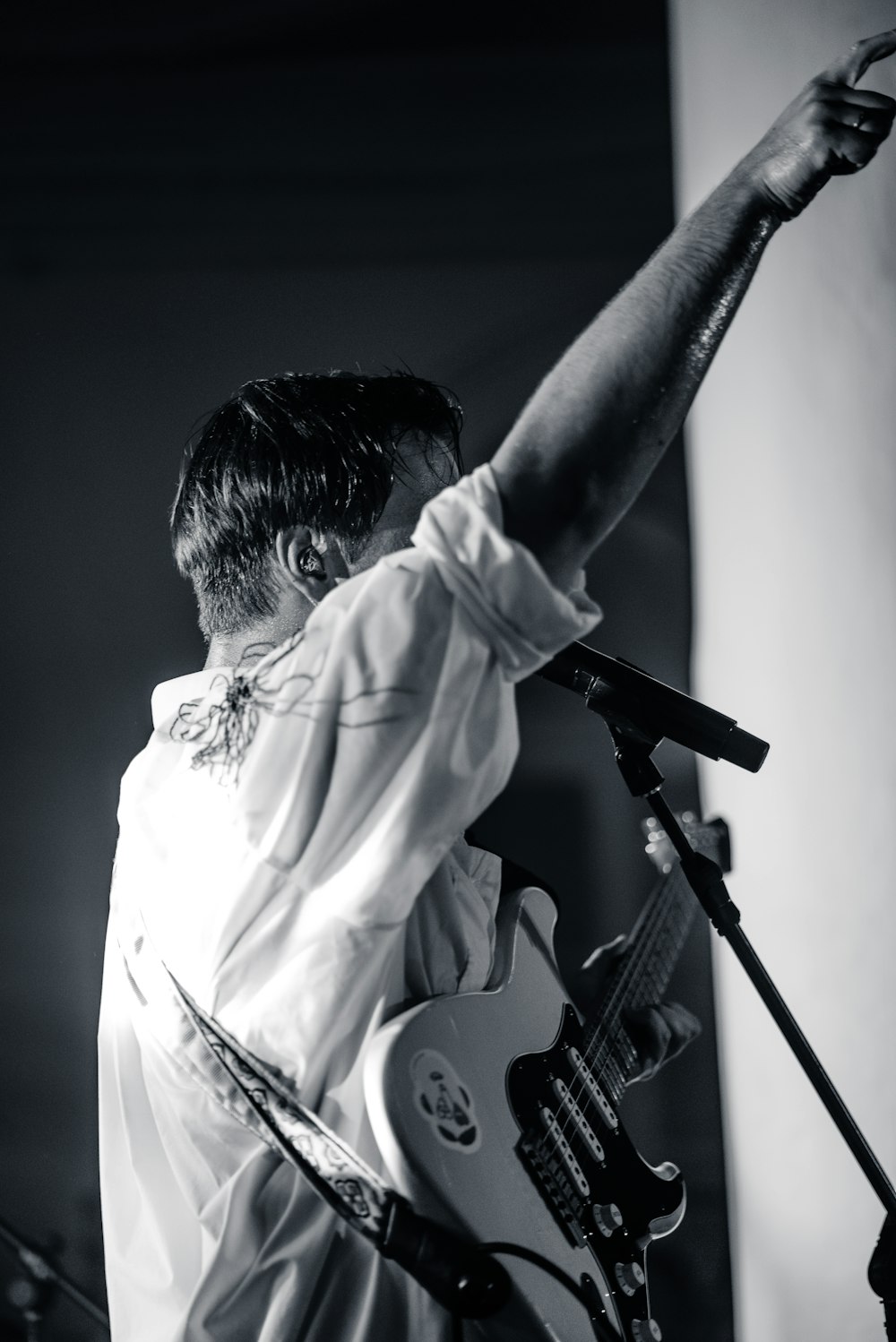 man in white dress shirt holding white electric guitar