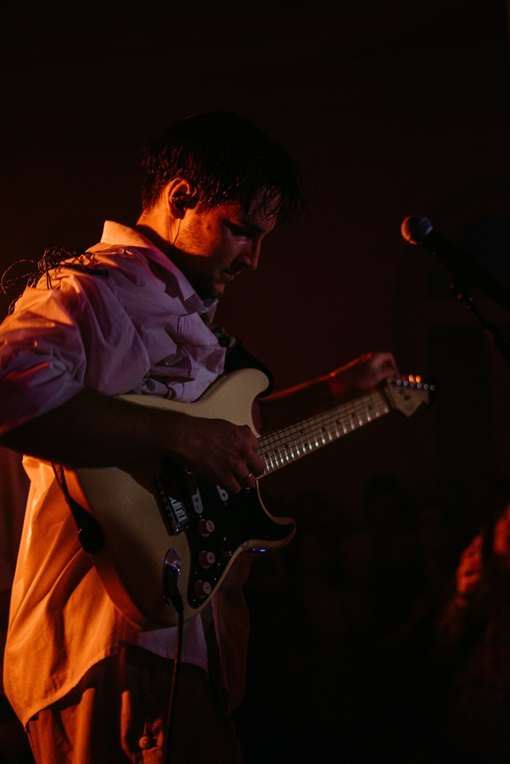 man in blue dress shirt playing electric guitar