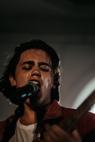 A close-up of Shadmehr singing passionately on stage.