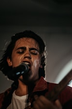 Stephanie Sanders performing under warm, moody stage lighting, eyes closed in deep emotion.