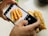 A person's hands holding a smartphone capturing a photo of a plate with several long, golden-brown fried dough sticks on a speckled countertop.