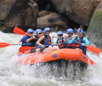 people riding orange kayak on river during daytime