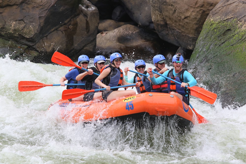 people riding orange kayak on river during daytime