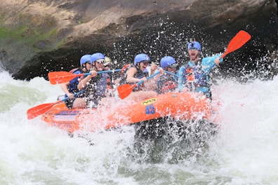 people riding orange kayak on water during daytime