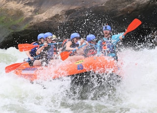 people riding orange kayak on water during daytime