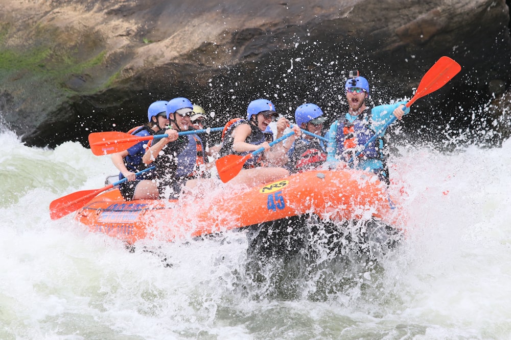 Menschen, die tagsüber mit orangefarbenem Kajak auf dem Wasser fahren